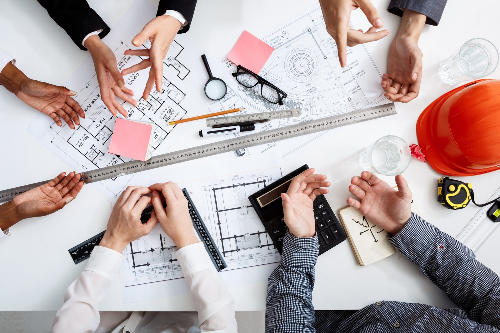 Picture of businessmen's hands on white table with documents, coffee and drafts